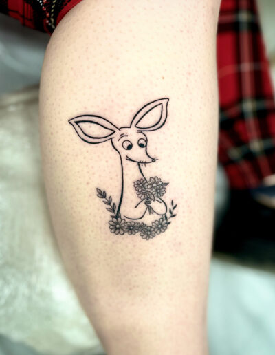 Minimalistyczny, konturowy tatuaż - ryjek, Muminki na łydce wykonany w studiu Omerta Tattoo, Wrocław