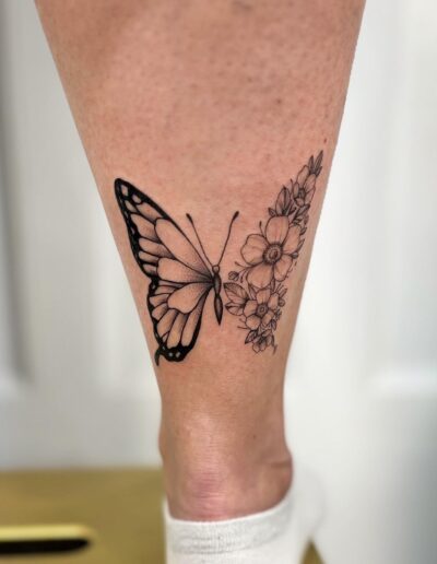 Minimalistyczny tatuaż motyla z kwiatami, kobiecy damski wykonany w studiu Omerta Tattoo, Wrocław
