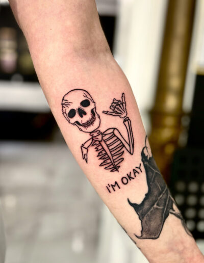 Minimalistyczny, konturowy tatuaż kościotrupa na przedramieniu wykonany w studiu Omerta Tattoo, Wrocław