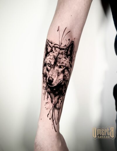 Graficzny tatuaż wilka na przedramieniu wykonany w studiu Omerta Tattoo, Wrocław